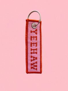 a pink keychain with the words keep on it hanging from a metal hook