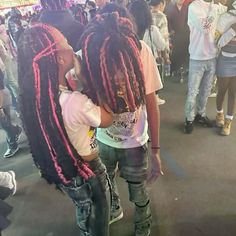 two girls with pink dreadlocks standing next to each other in a crowded area