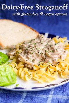 a white plate topped with pasta and meat covered in gravy next to lettuce