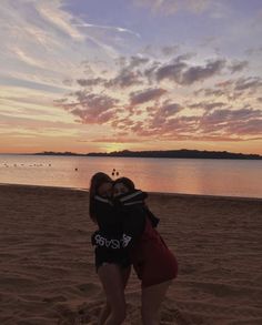 two women hugging on the beach at sunset