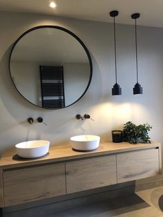 two white bowls sit on top of a wooden counter in front of a round mirror