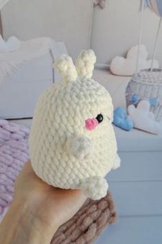 a hand holding a white crocheted stuffed animal