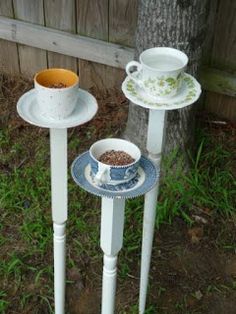 two white bird feeders sitting next to each other on top of a grass covered field