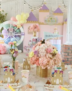 a table topped with lots of pink flowers and paper plates covered in confetti