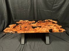 a wooden table sitting on top of a metal stand next to a black backdrop with white and brown designs