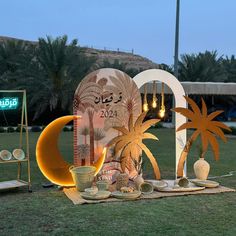 an outdoor setting with palm trees, moon and other decorations on the grass in front of it