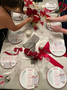 the table is set with red roses and place settings for guests to sit down at