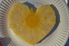 a heart shaped pineapple cut in half on a paper plate