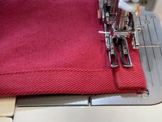 the sewing machine is working on the red material that has been stitched together to make it easier for someone to sew