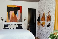 a white bed sitting in a bedroom next to a painting