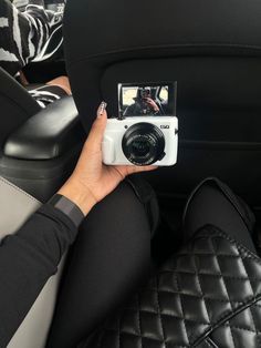 a person taking a photo in the back seat of a car with a digital camera