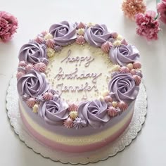 a birthday cake with purple frosting and flowers