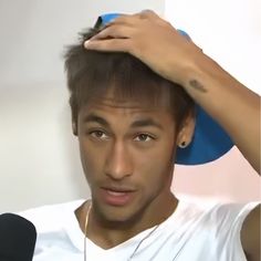 a young man is holding his hair in front of him and looking at the camera