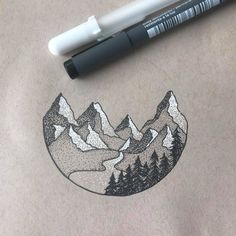 a drawing of mountains and trees on a piece of paper next to a marker pen