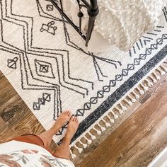 a person standing on the floor in front of a bed with a white and black blanket