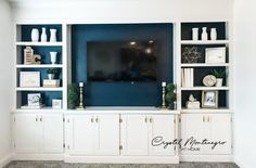 an entertainment center with white cabinets and blue walls