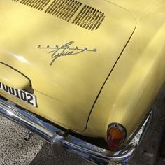 an old yellow car is parked on the street