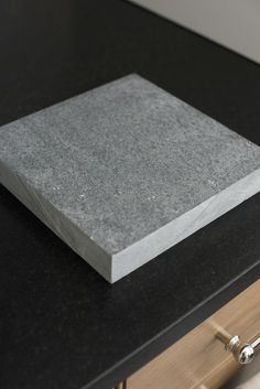 a close up of a black counter top with a square stone on it's side