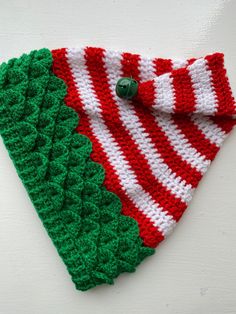 a crocheted red and white scarf with green leaves on the bottom is shown