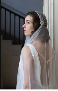 a woman wearing a veil with a flower in her hair is looking off into the distance