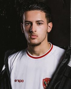 a young man in a white shirt and black jacket looking at the camera with serious expression on his face