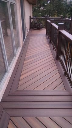 a wooden deck with railings and sliding glass doors on the side of a house