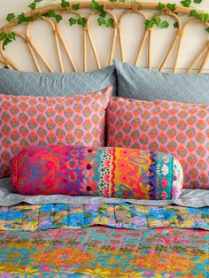 a bed with colorful pillows on top of it next to a bamboo headboard and wicker head board