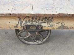 an old wooden table with metal wheels and writing on the top that says natting