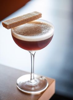 a close up of a drink in a glass with a cracker on the rim