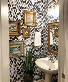 a bathroom decorated in blue and white with pictures hanging on the wall above the sink