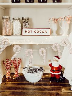 a shelf with candy canes, hot cocoa and santa clause on it's mantle