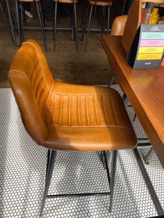 a brown leather chair sitting on top of a wooden table next to bar stools