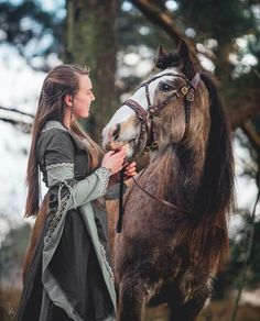 a woman standing next to a brown horse