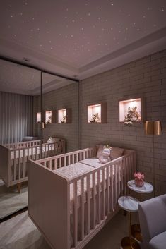 a baby's room with two cribs in the corner and lights on