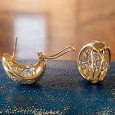 two pairs of earrings sitting on top of a blue cloth