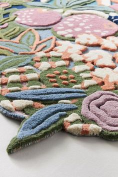 a colorful rug with flowers and leaves on the bottom is laying on a white surface