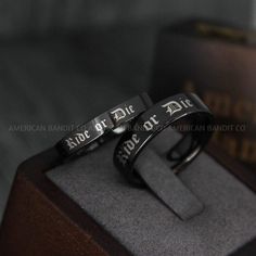 two black rings with the words ride or die engraved on them sitting on top of a box