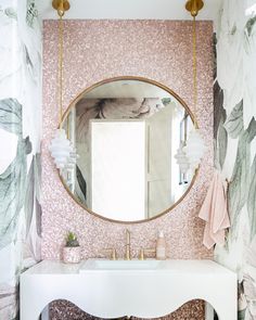 the bathroom is decorated with pink and green wallpaper, gold accents and a round mirror