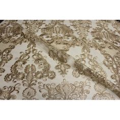 an embroidered fabric with gold and white designs on the bottom, along with other material