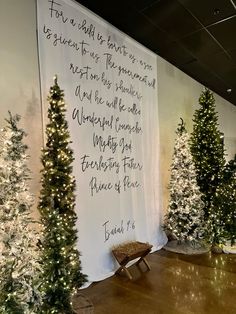 christmas trees are on display in front of a wall with a message written on it