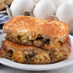 two sandwiches stacked on top of each other with eggs in the backgroung