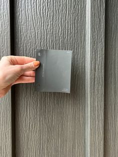 a hand is holding an electronic device in front of a metal paneled door that has been painted silver