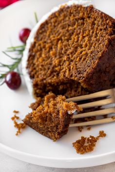 a piece of cake on a white plate with a fork in it and some cranberries next to it