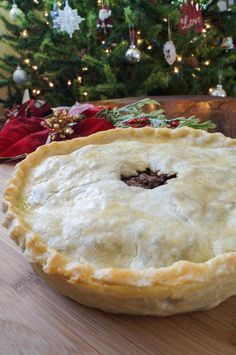 a pie sitting on top of a wooden table next to a christmas tree