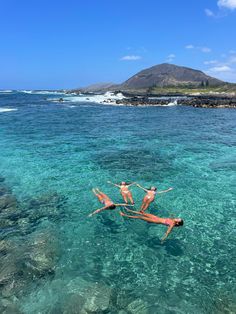 three people are floating in the clear blue water