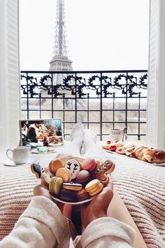 a person holding a plate with food on it in front of the eiffel tower