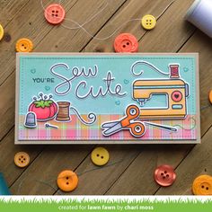 a card with buttons and sewing supplies on the table next to yarn, scissors, and thread