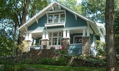 a blue house with white trim and windows in the front yard is surrounded by trees