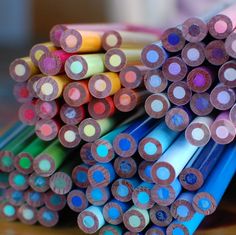 there are many different colored pencils stacked on top of each other in this photo