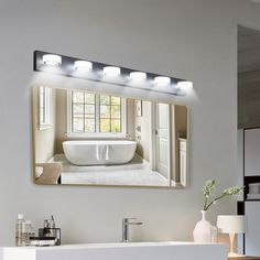 a bathroom with a sink, mirror and bathtub in the reflection on the wall